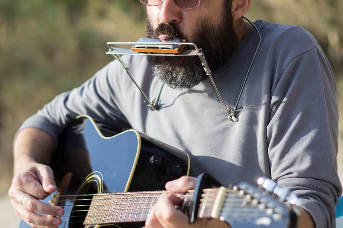 Musicista folk suona chitarra e armonica